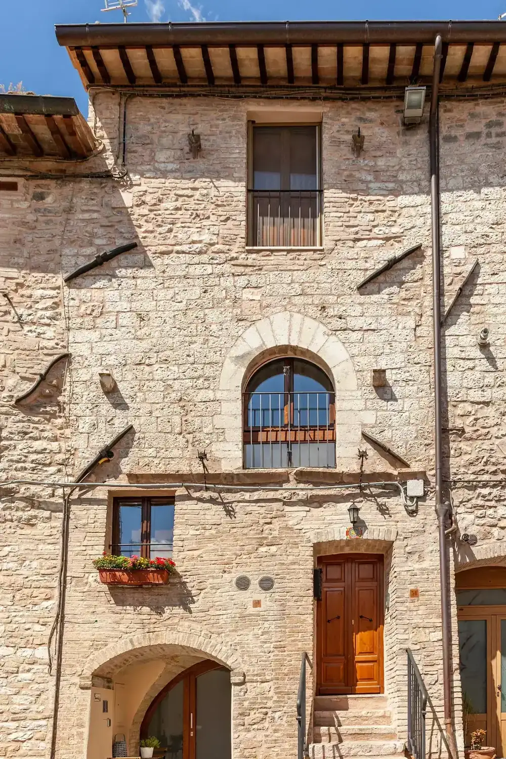 Ingresso su strada dell'edificio in pietra rosa del Subasio