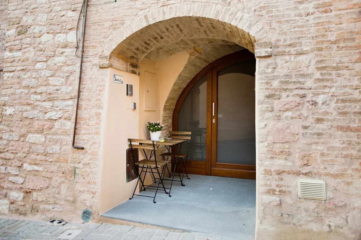 Ingresso privato su strada con arco in pietra e tavolino esterno